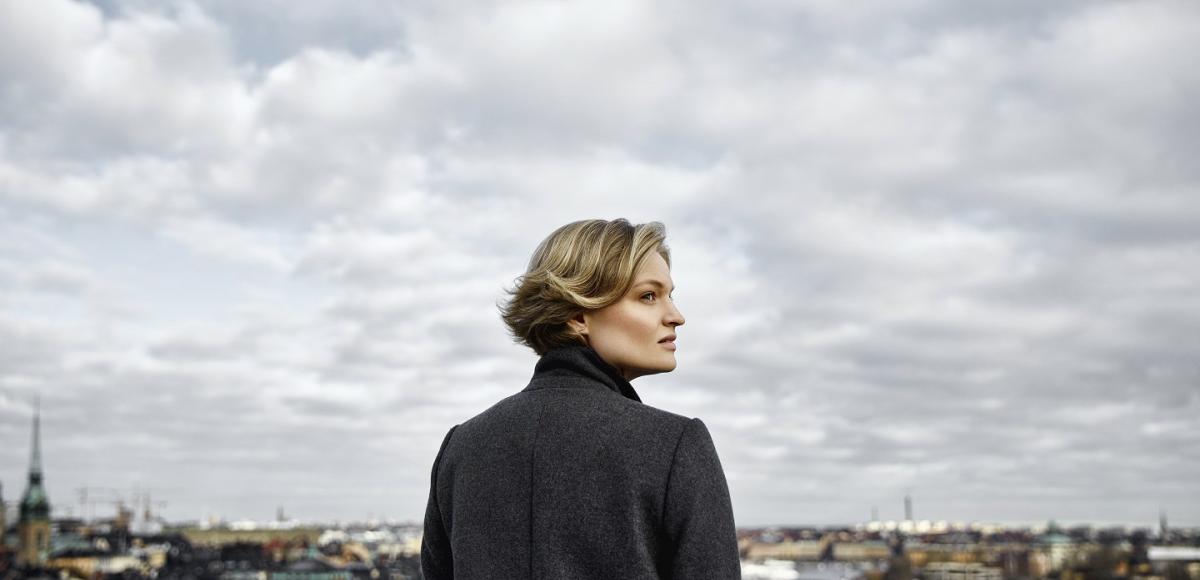 Woman on rooftop looking out towards cloudy sky