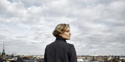 Woman on rooftop looking out towards cloudy sky