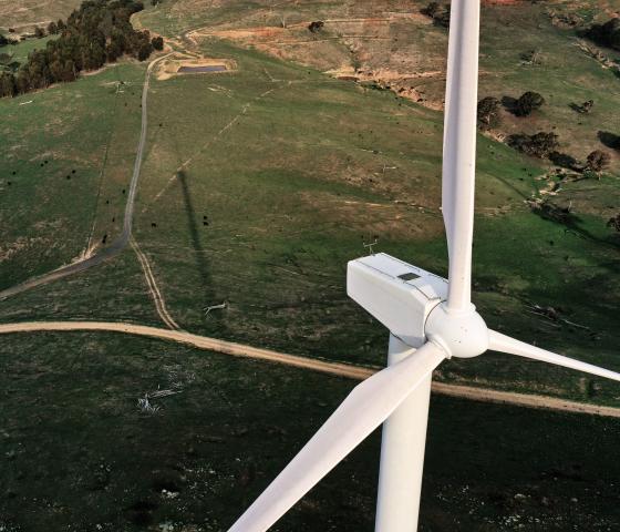 Arial shot of a wind turbine on a backdrop of green fields