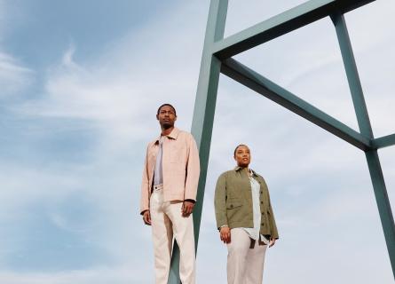 Expansive light blue-sky backdrop, with a man and a woman in the foreground standing next to a metal structure