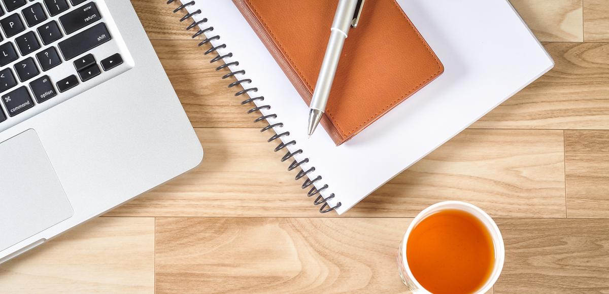 computer beside notebook and cup of tea