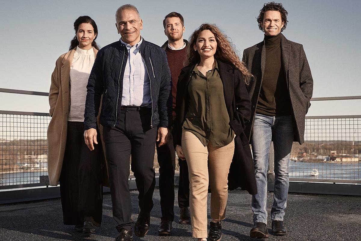A group of five adults walking on a roof terrace 
