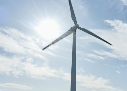 Expansive light blue-sky backdrop, with a wind turbine in the foreground
